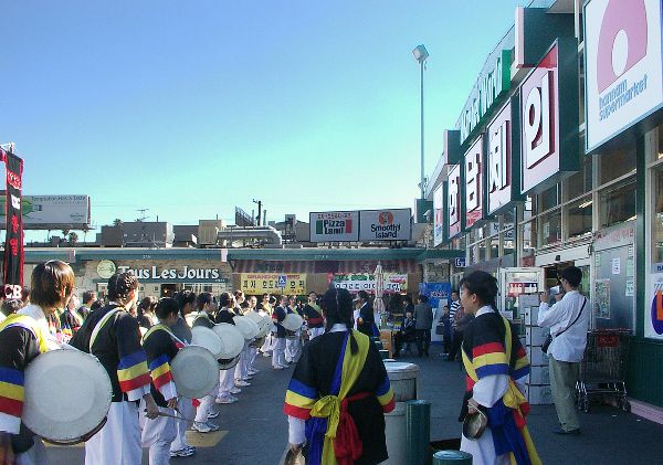 Fig. 8.3. A large group of male and female college students, most or all of them Asian in appearance, stands in front of a Korean grocery store, holding drums.
