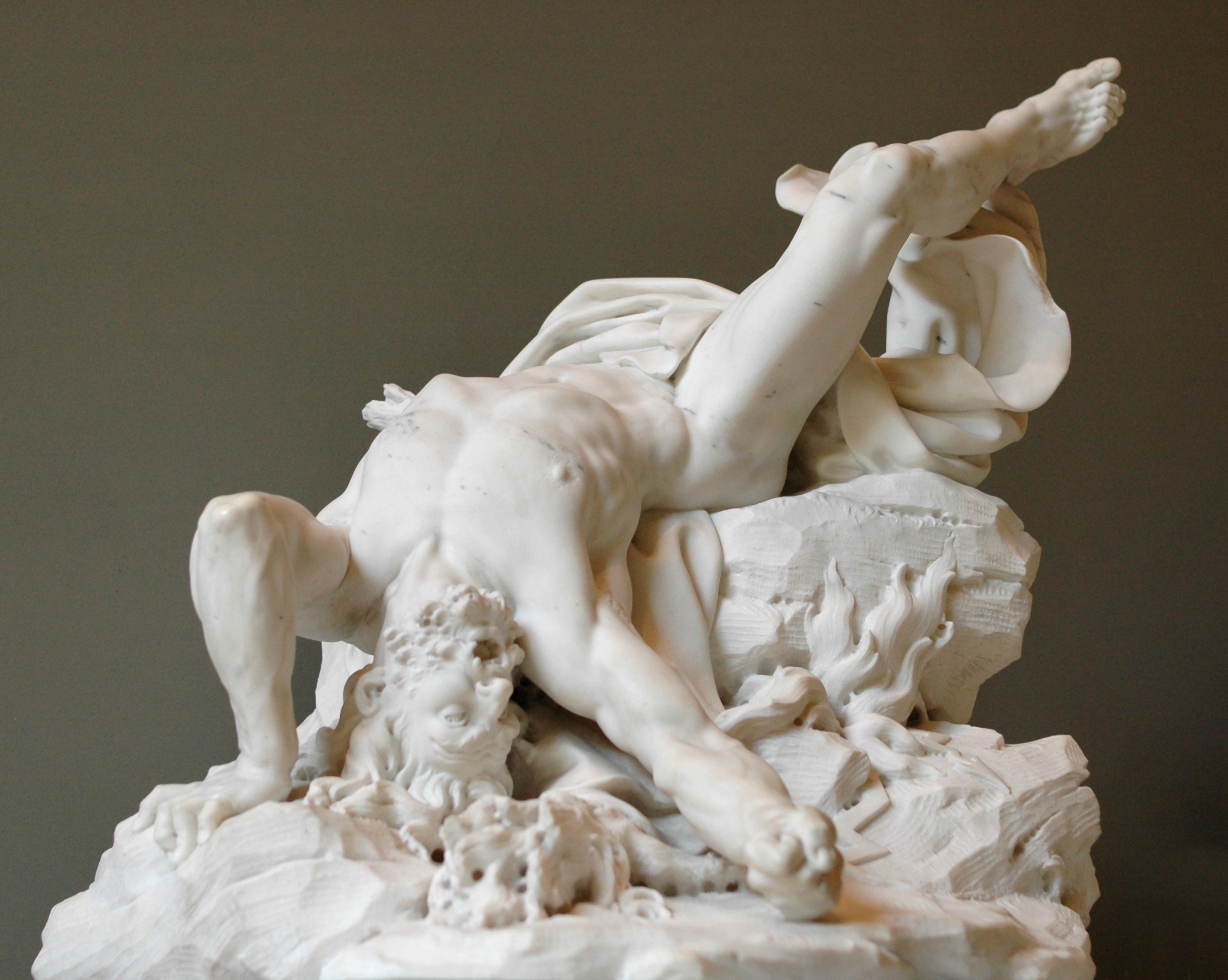 Statue of a god writhing in pain on the ground, looking as if he's fallen from the sky