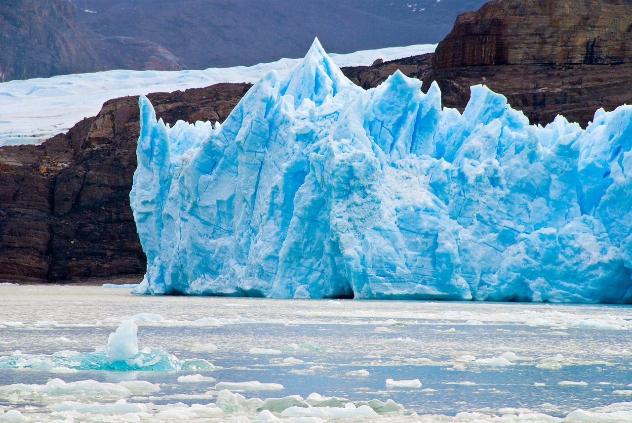 A photo of a light blue iceberg is the sea, surrounded by ice chunks.
