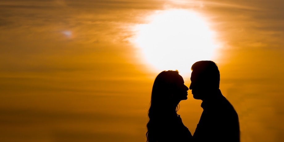 A silhouette of a couple in front of a sunset.