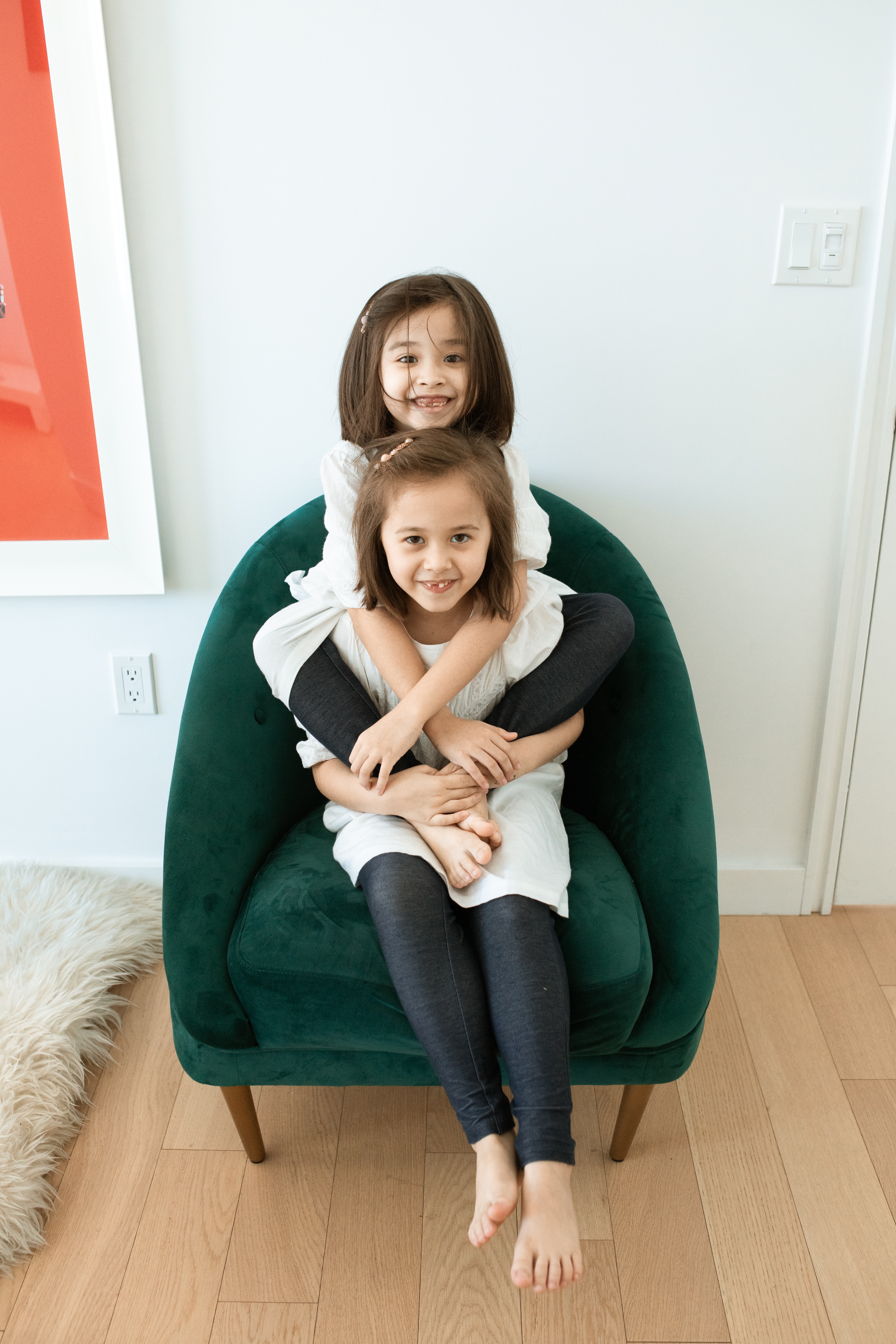 A Girl Piggy Back Riding Another Girl While Sitting on Green Armchair
