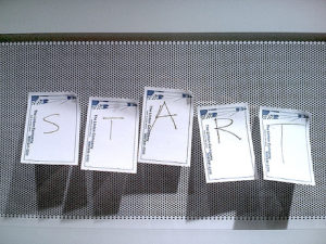 Five sticky notes on a billboard. Each contains a letter to spell out "START"