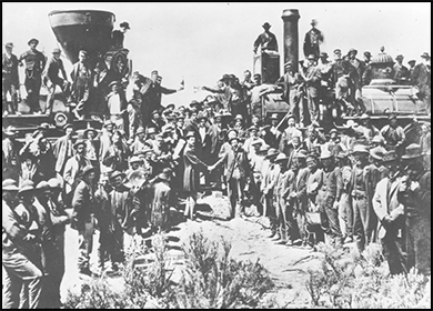 Una fotografía muestra la ceremonia conmemorativa de la finalización del primer ferrocarril transcontinental. Samuel S. Montague y Grenville M. Dodge, ingenieros jefe de los Ferrocarriles del Pacífico Central y Union Pacific, respectivamente, se dan la mano simbólicamente frente a dos locomotoras y una multitud de trabajadores.