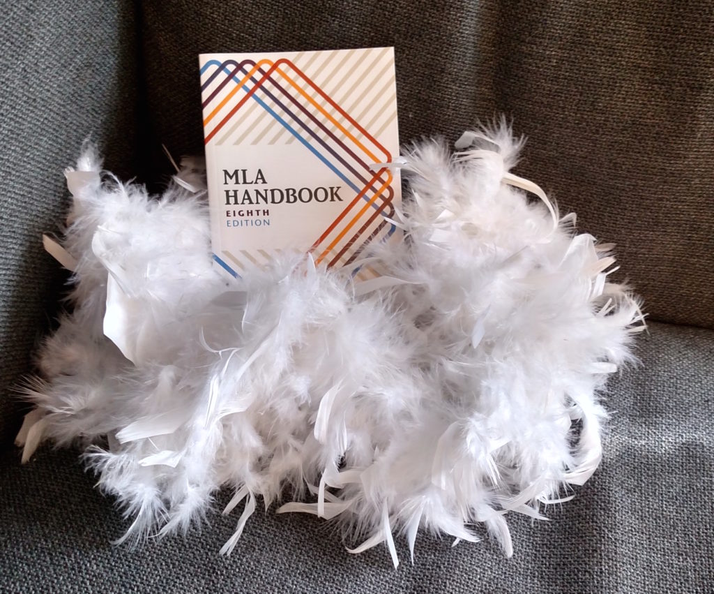 MLA Handbook 8th Edition, surrounded by a white feather boa
