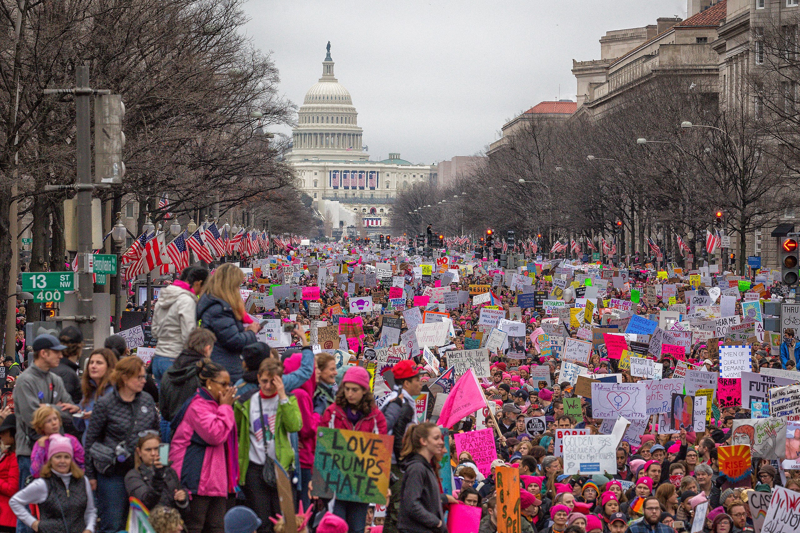 Thousands of women marching on Washington protesting with signs and pink hats