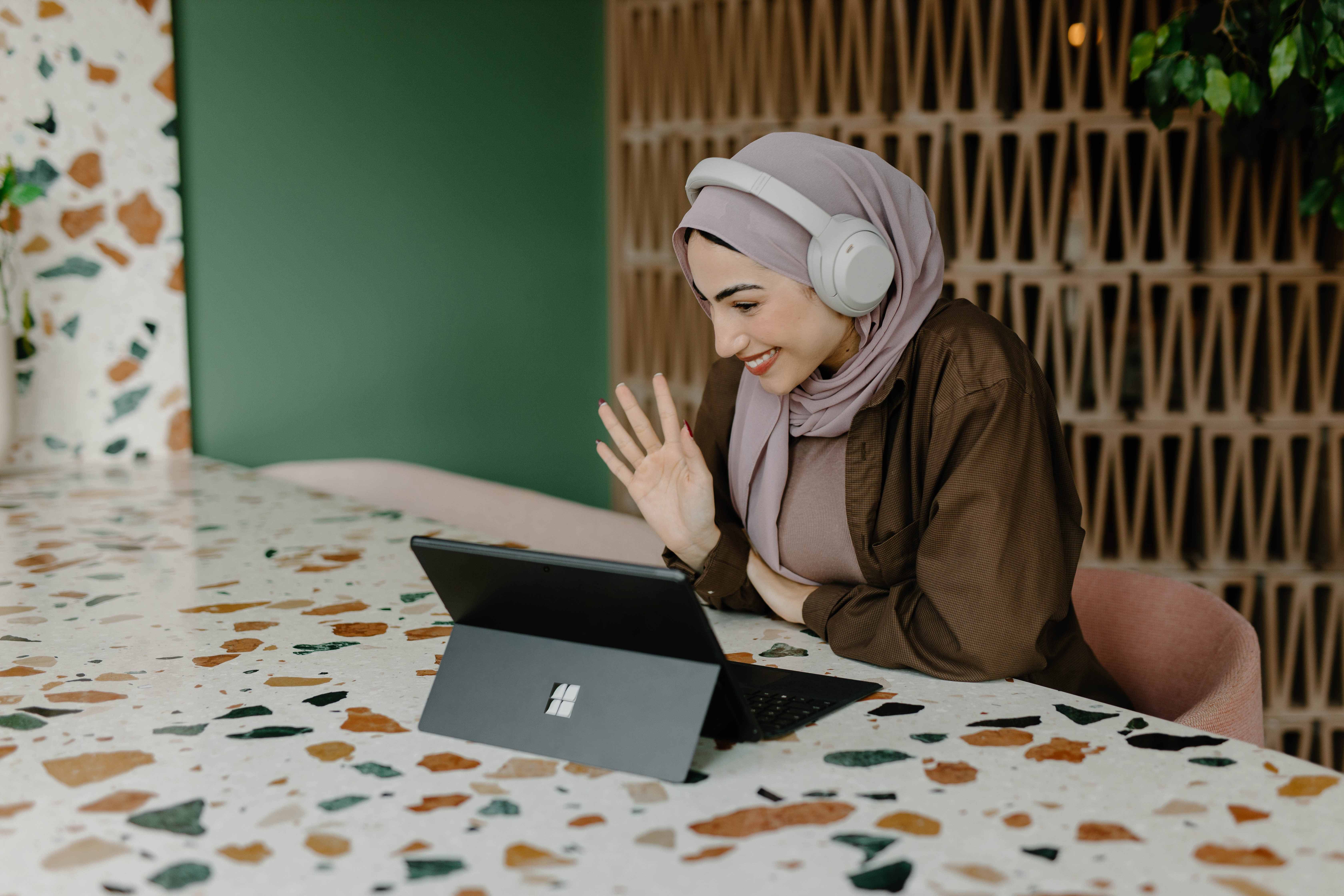 woman smiling with a computer and headphones