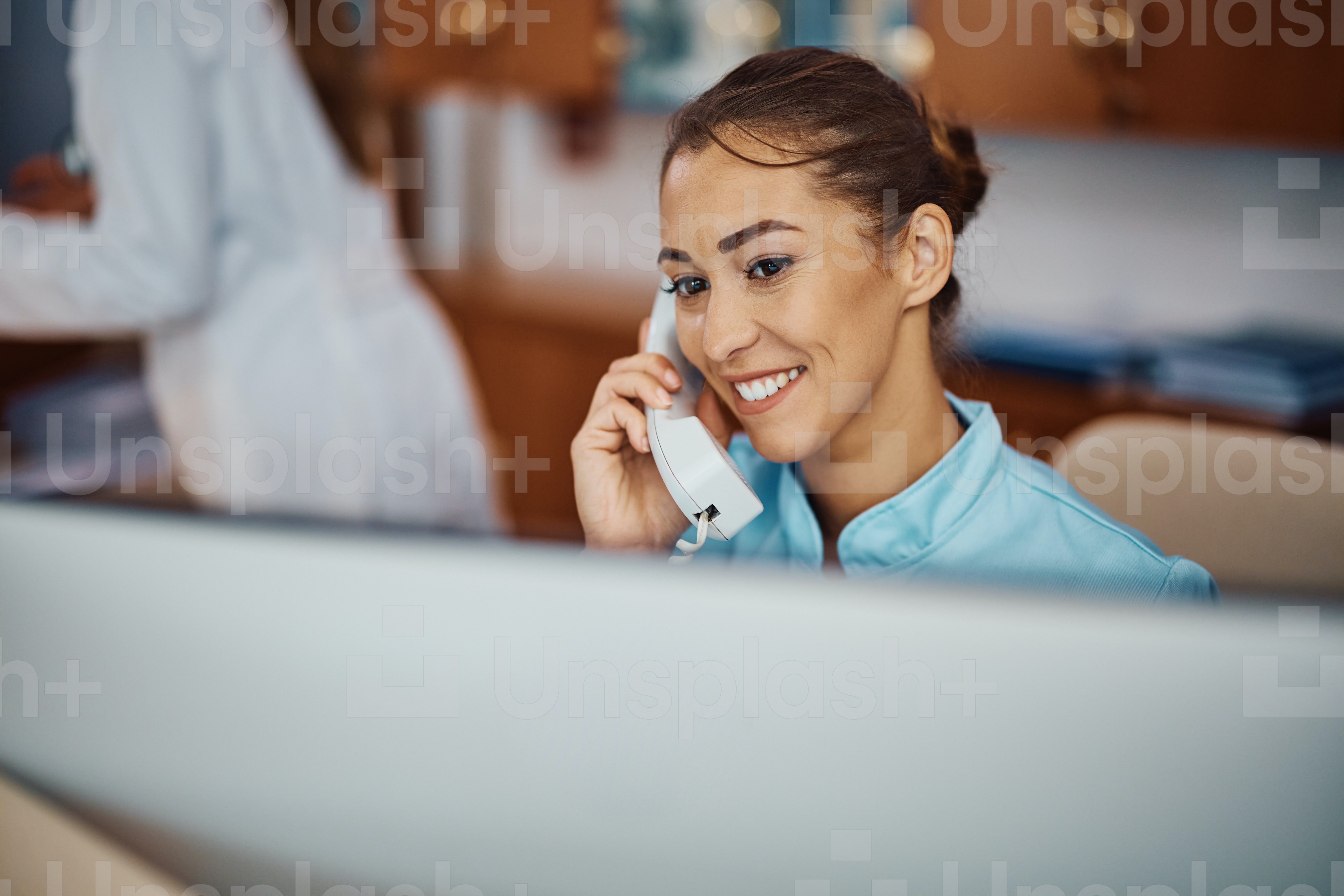 Nurse answering a phone call at the reception desk in a hospital