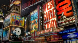 Billboard display of posters for Broadway shows. From left to right the posters read, "Hair," "The Phantom of the Opera," "South Pacific," "West Side Story," and "Chicago."