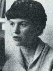 A black-and-white photo of Sylvia Plath with her hair up, looking to the left of the camera lens