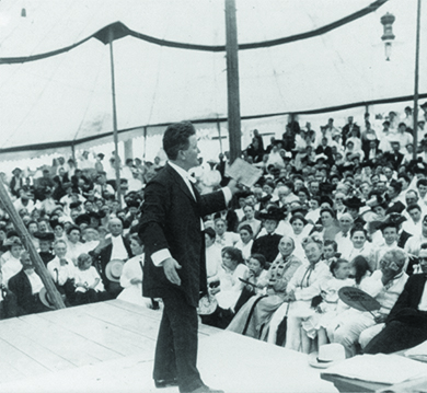 Une photographie montre Robert La Follette s'adressant de façon animée à une foule nombreuse.