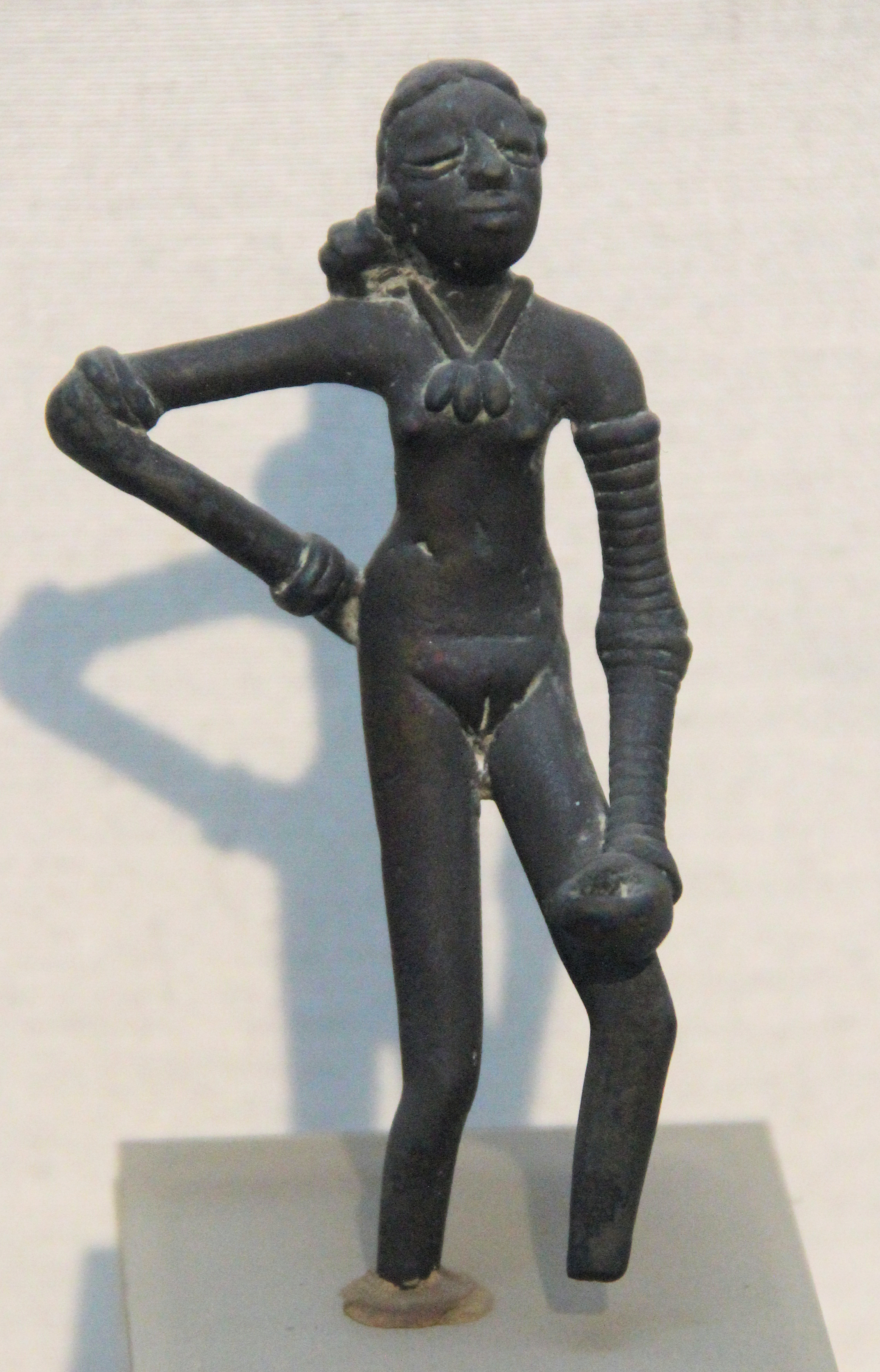Bronze statue of a girl with bangles on her arm.