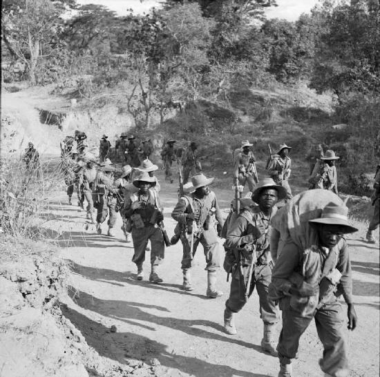 Armed African troops, carrying backpacks and wearing hats, marching through the jungles of Myanmar during World War II. Details in the text.