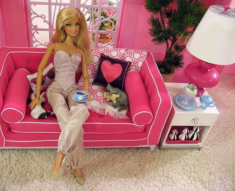 Barbie doll in summer outfit sitting on a pink couch.