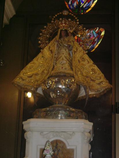 Dark figure in a gold dress on a pedestal