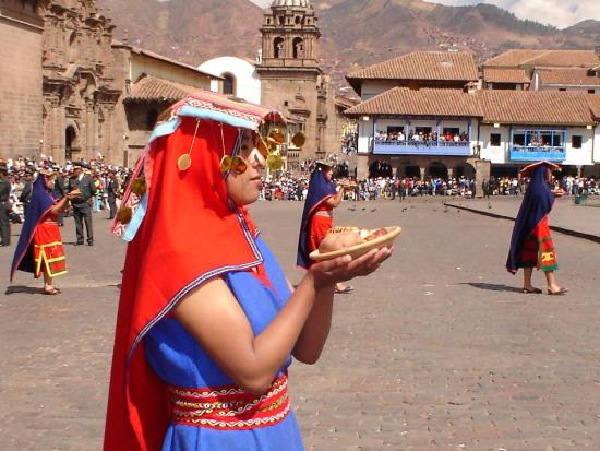 Person dressed in red and blue holds a plate of bread in a town square