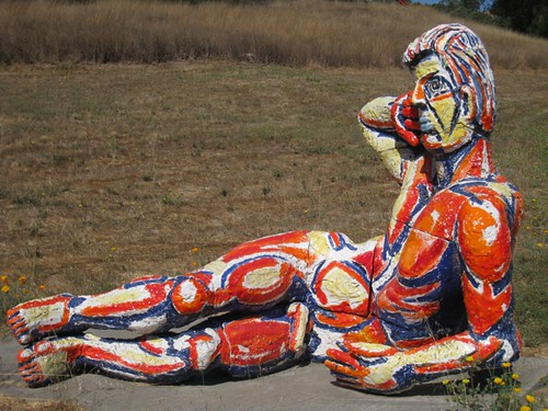 a nude man reclingin on the ground with red, white, and blue paint