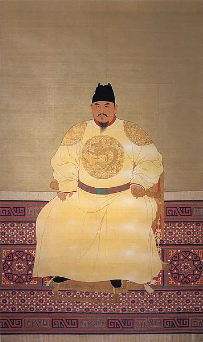 An image of a painting is shown. In the image a man sits on a brown chair on an intricately detailed red, black, and white rug along a pale brown wall. The figure wears a black cap, has a black thin moustache and feathery beard. He wears a yellow, long shirt dress with a gold design on the front and on each of his shoulders. He wears a red and green belt and black shoes. A red collar is seen around his neck.