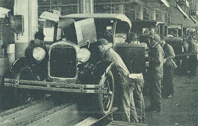 Uma fotografia mostra trabalhadores da linha de montagem produzindo automóveis Ford.