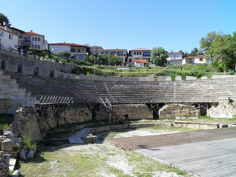 Present-day picture of an ancient Greek theater with houses in the background.