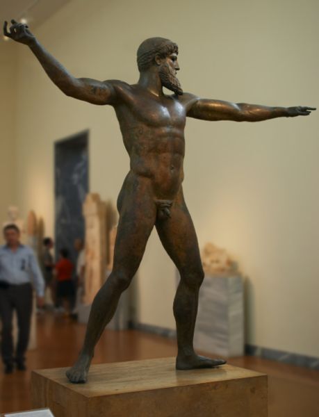 Bronze statue of an athletic nude male with a beard with his right arm in position to hurl a thunderbolt or a trident.
