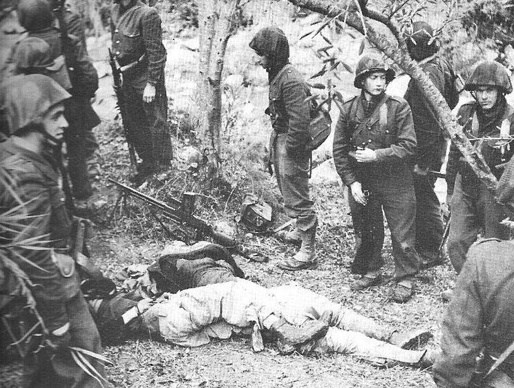 French soldiers standing nonchalantly next to the bodies of Algerians.