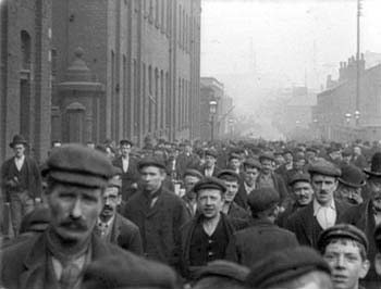 Crowd of English working men outside of a factory, with a boy of about 12 years among them.