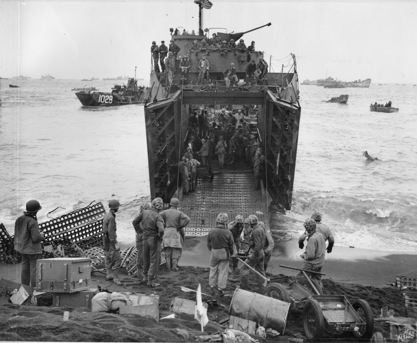 US Marines unload supplies from a landing ship's ramp on the beach in Iwo Jima. Details in text.
