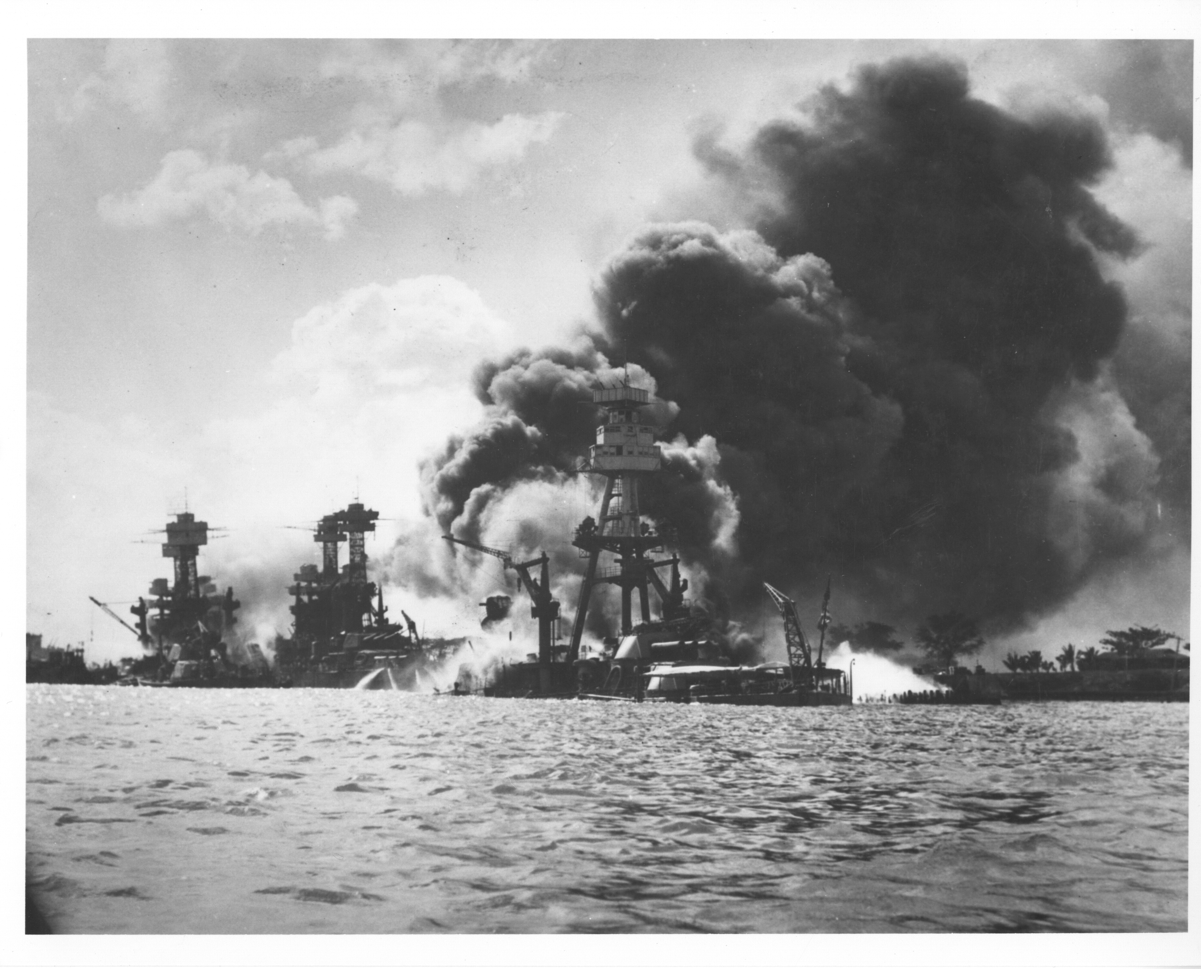 3 US naval ships engulfed in fires and thick dark smoke clouds in Pearl Harbor. Details in text.