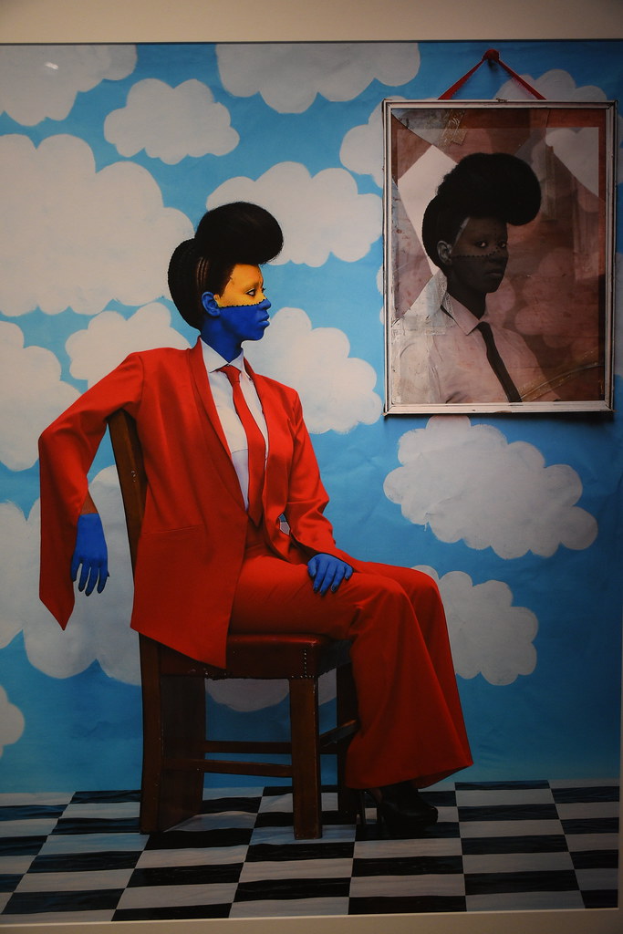a woman in a red suit sitting in a chair againts a sky