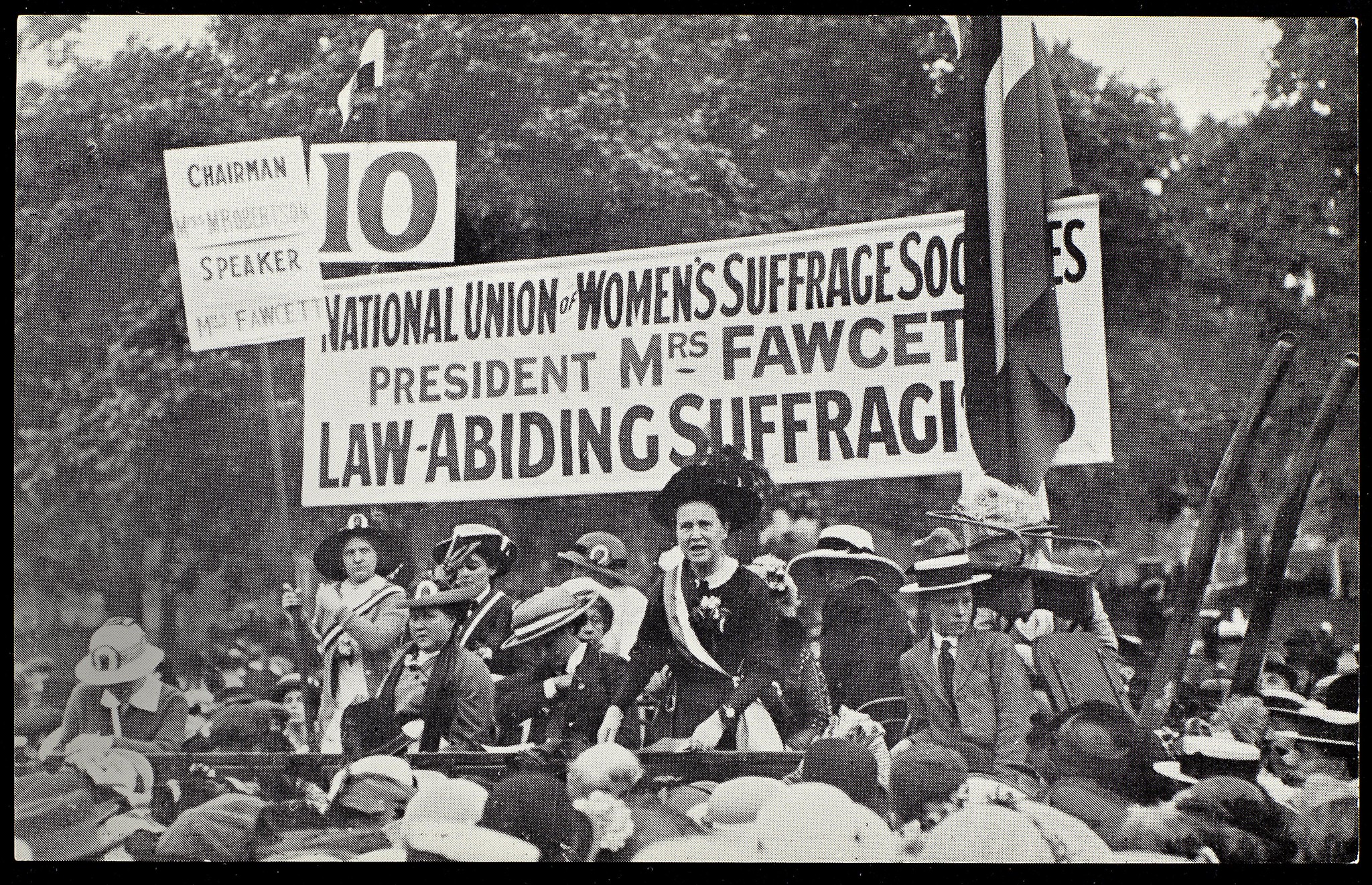 women riding on a float with a large sign during a protest