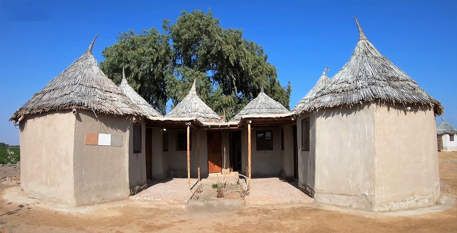 mud brick building in a hexagon shape with thatched roofing