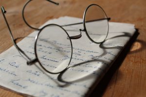 Old wire-rim eyeglasses sitting on paper with old handwriting