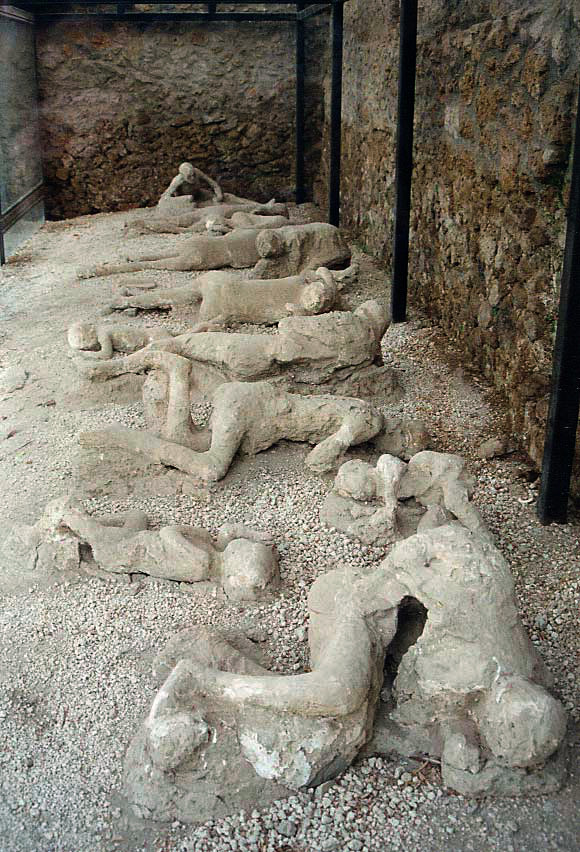Image of the preserved remains of people killed in the eruption of Mount Vesuvius, lying on the ground.