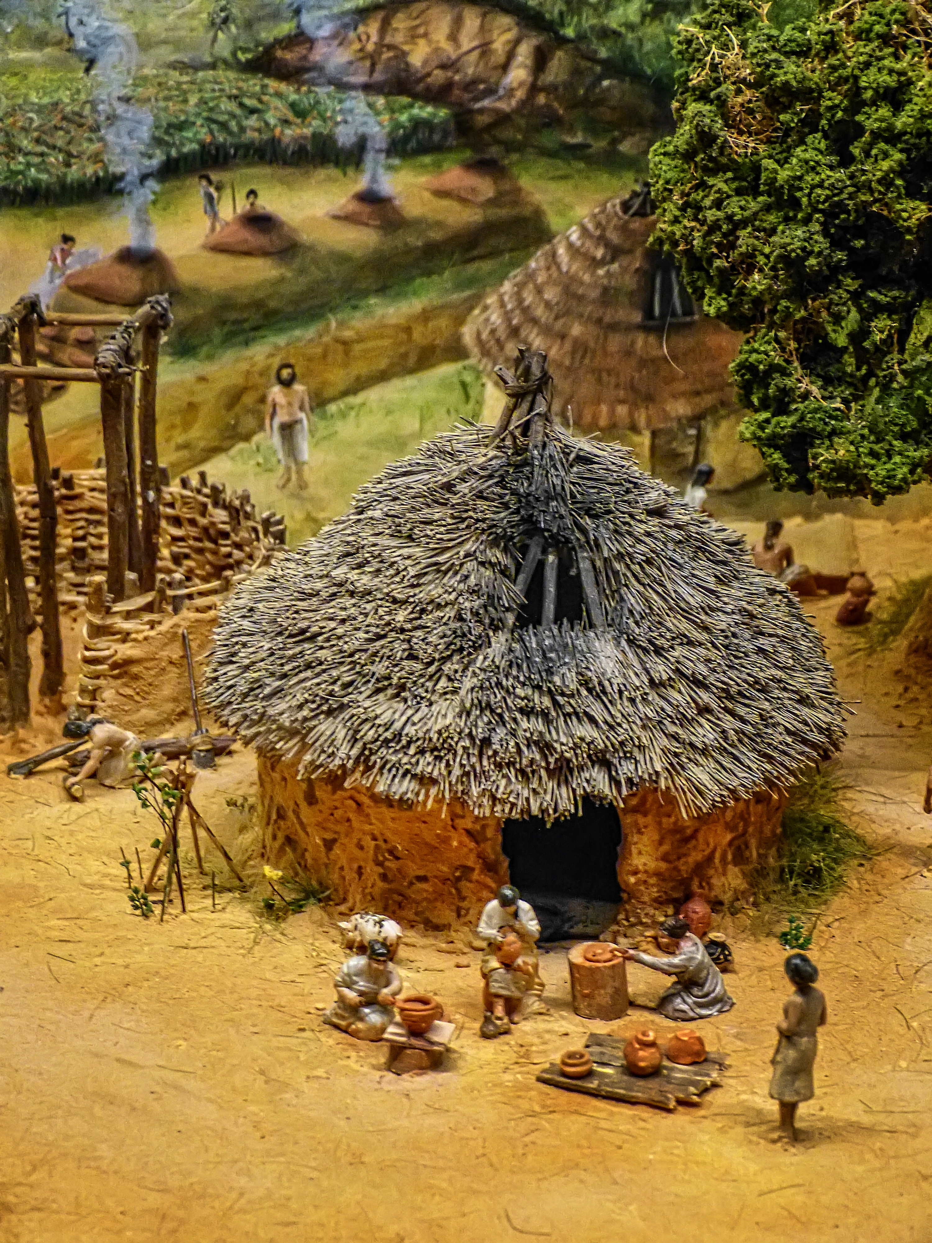 model of a hut and people cooking outside