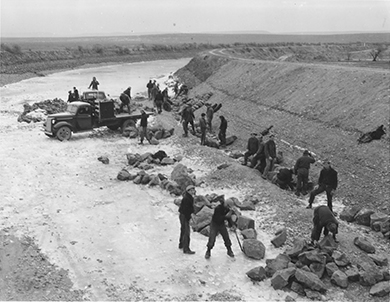 Une photographie montre un groupe de travailleurs de la CCC construisant un canal.