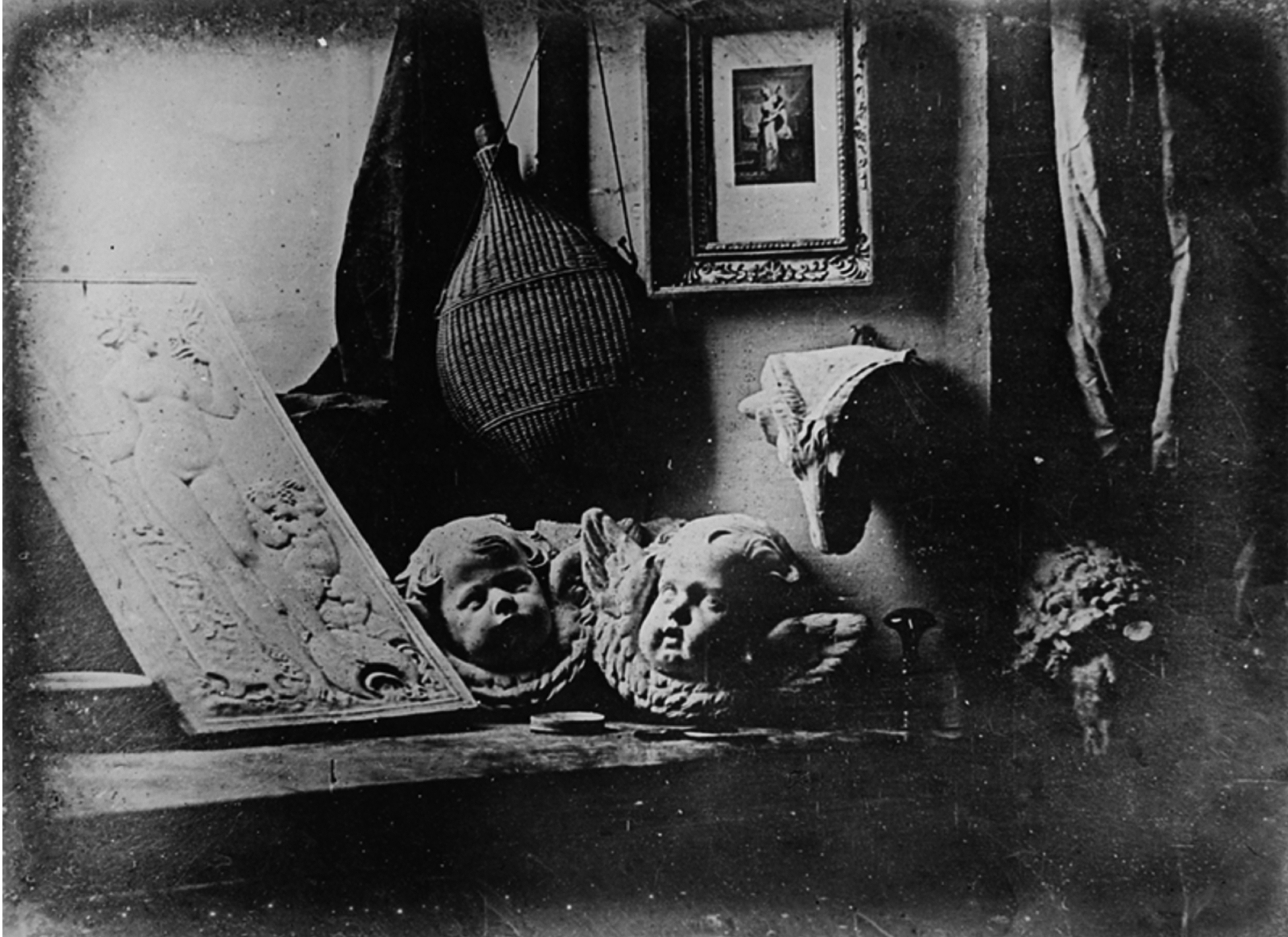 Black and white photograph of objects on a table and hanging from a wall.