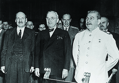 Una fotografía muestra a Clement Atlee, Harry Truman y Joseph Stalin de pie frente a un grupo de funcionarios.