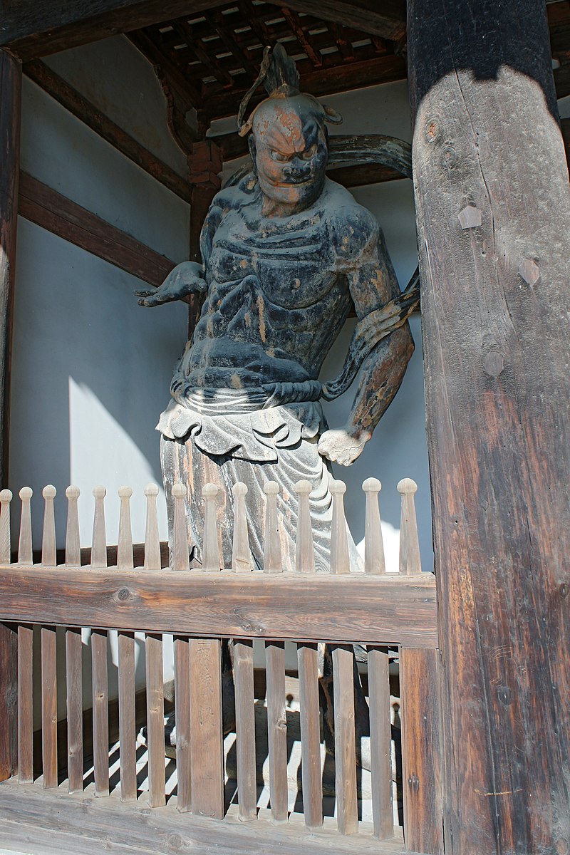 standing man in black behind a wooden gate