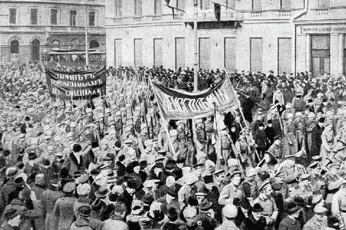 The photograph shows a street is packed with people. Several protesters hold large banners.