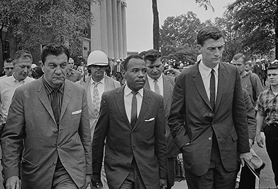 Une photographie montre James Meredith entrant à l'université du Mississippi, entouré d'un maréchal américain et du procureur général adjoint chargé des droits civils.