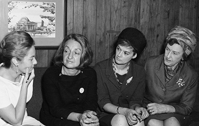 A photograph shows Betty Friedan and three other women engaged in conversation.