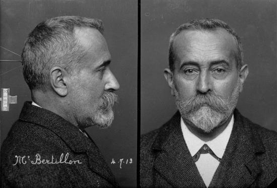 black and white photographic mugshot of white man with facial hair
