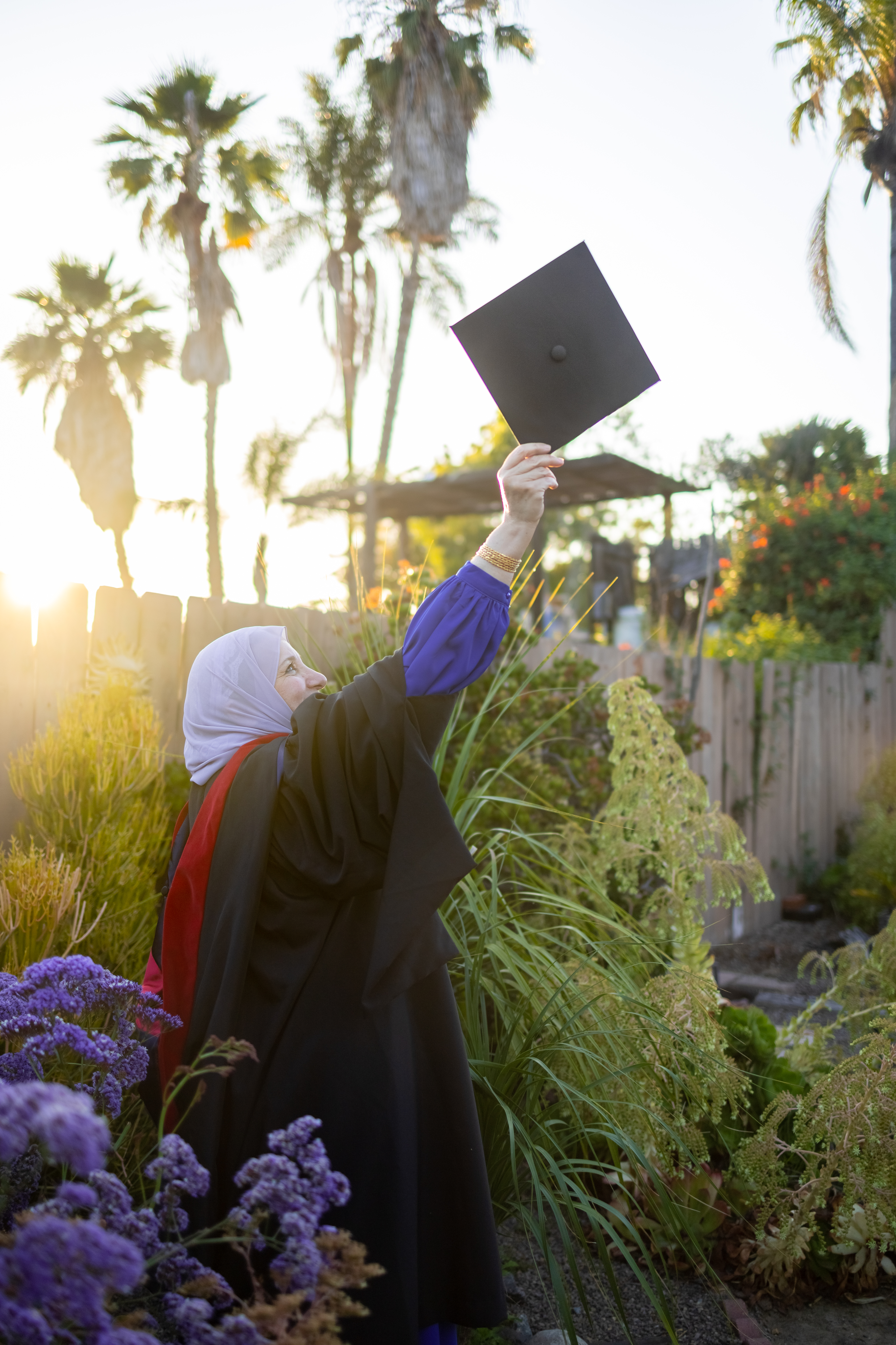 Hana Kassas in the backyard, raising her arm with the degree.