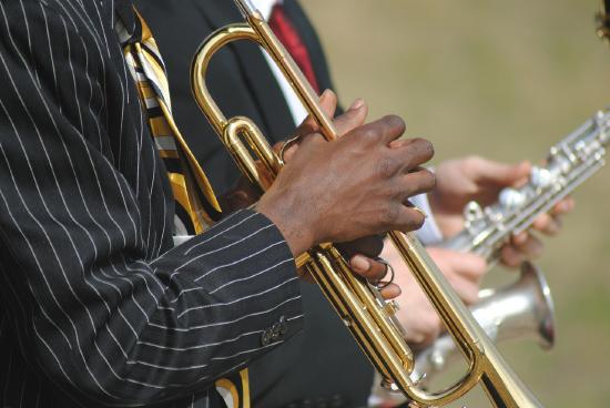 Musician hands on a trumpet and saxophone further behind