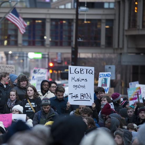 Protestors holding a sign showing they are LGBTQ Muslims against immigration bans