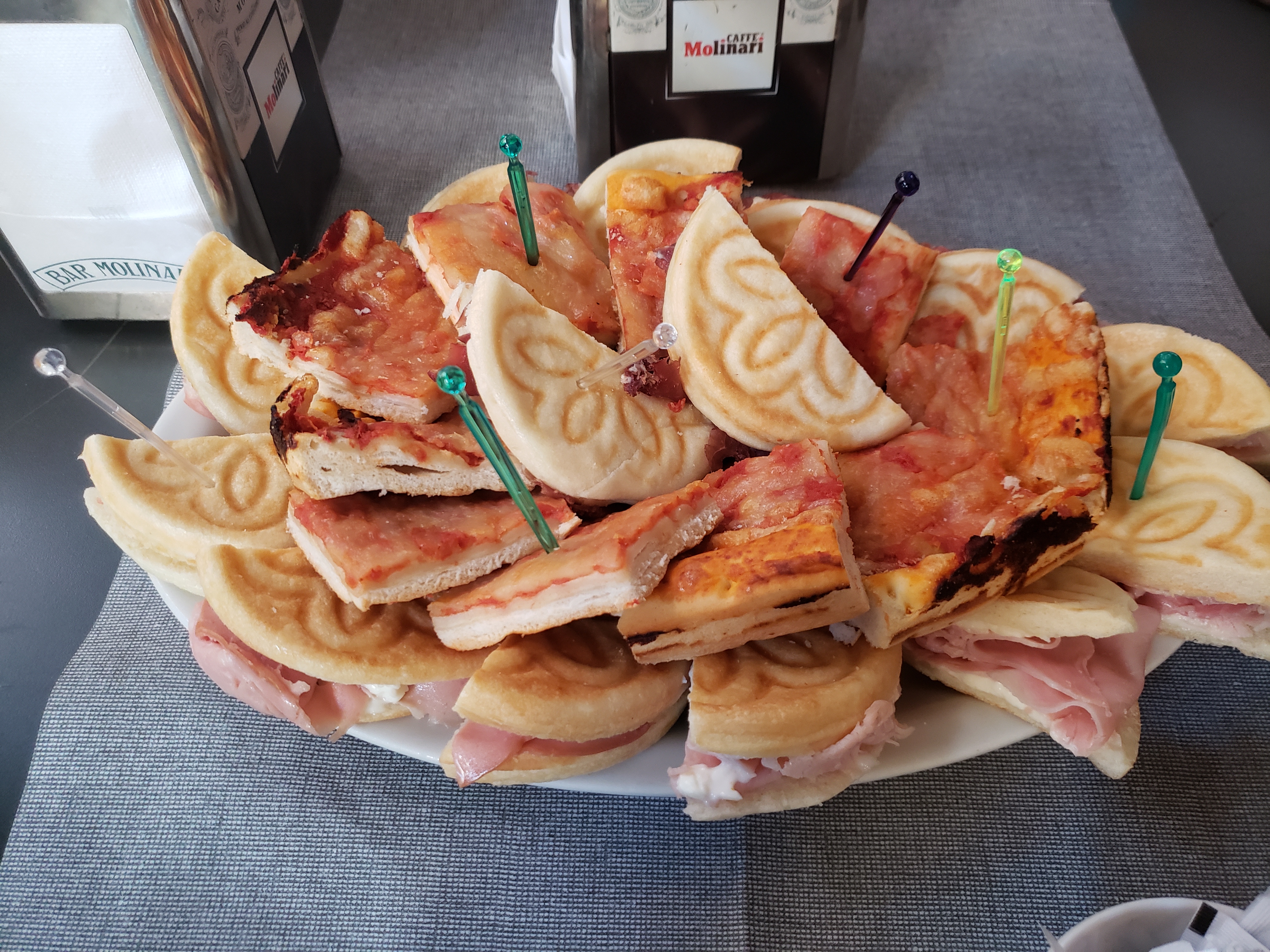 An assortment of Italian focacce, mini pizzas (pizzette), and savory pastries (rustici) on a plate.