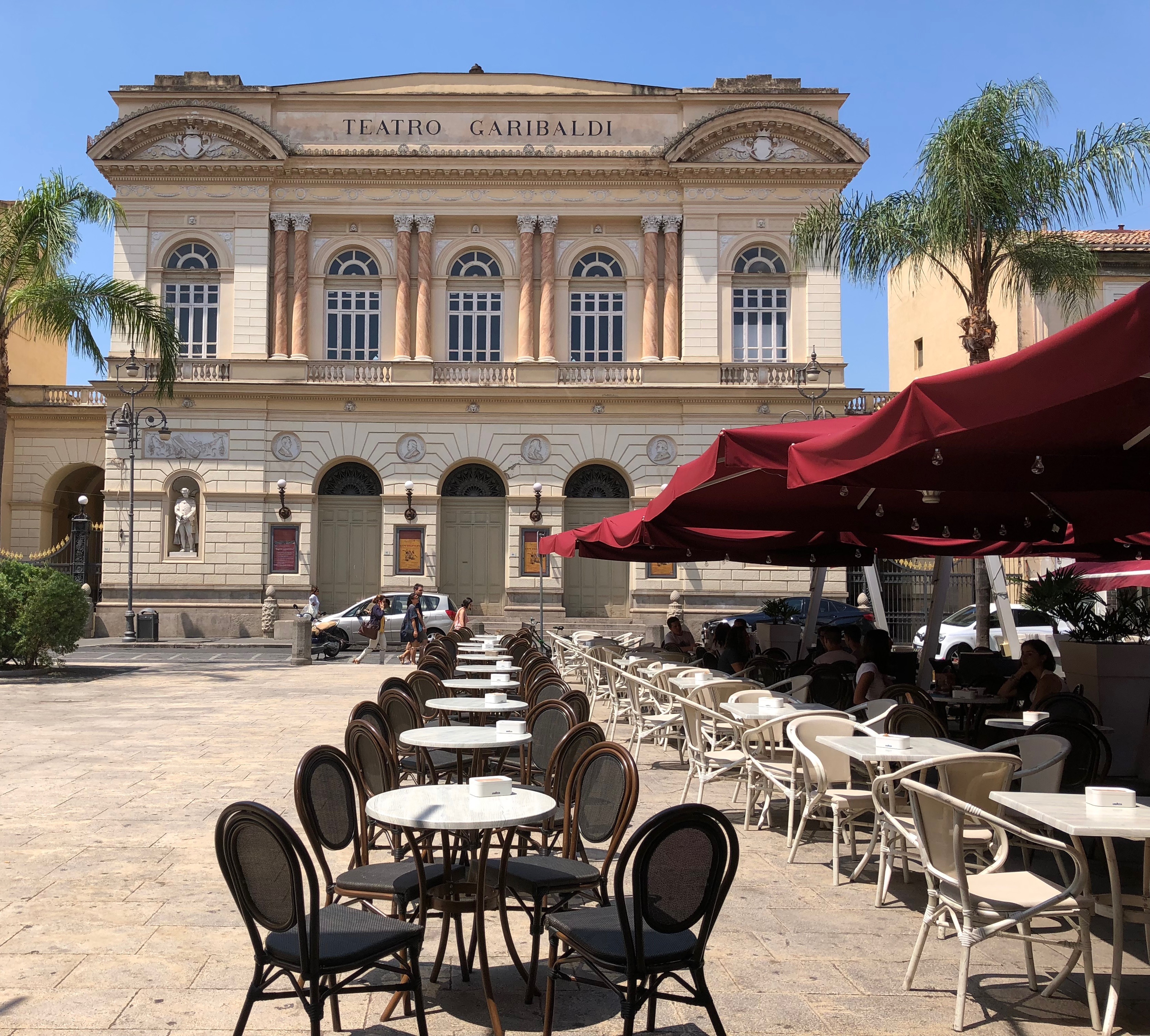 Outdoor coffee tables in an Italian piazza in front of a historic theater.