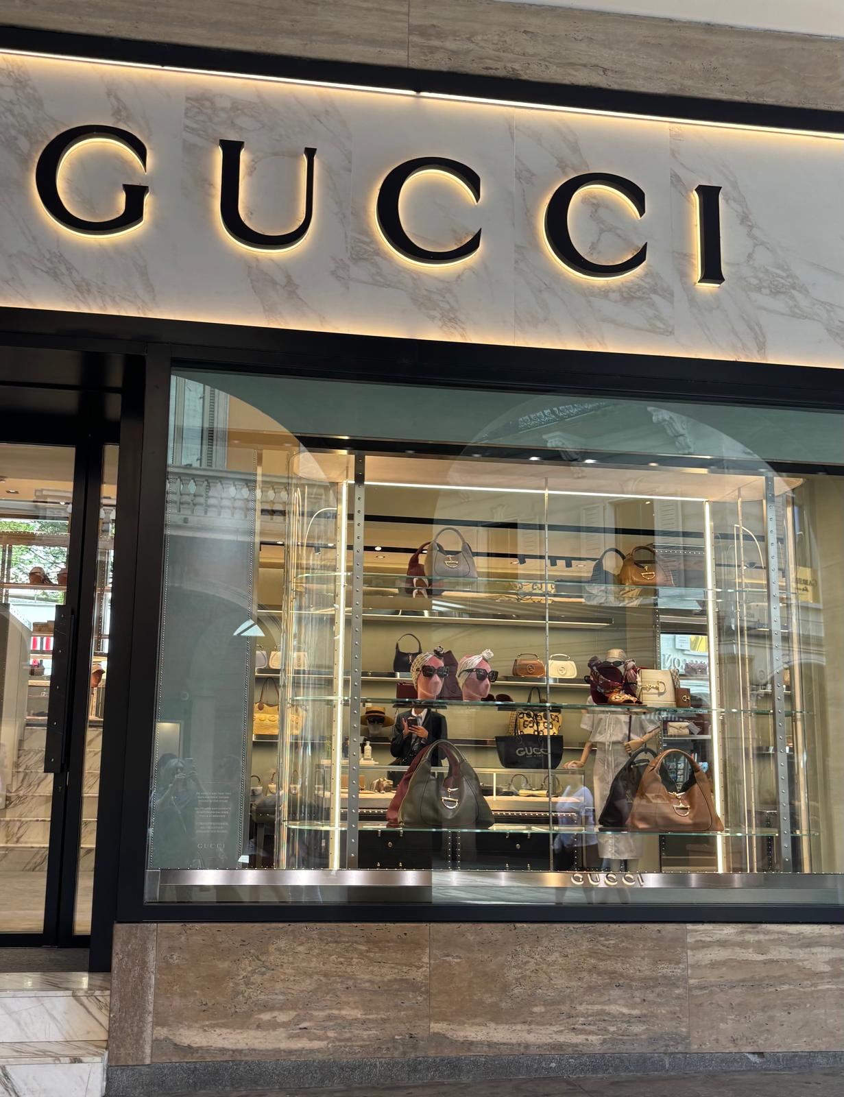 Gucci store display window featuring luxury items and elegant branding.