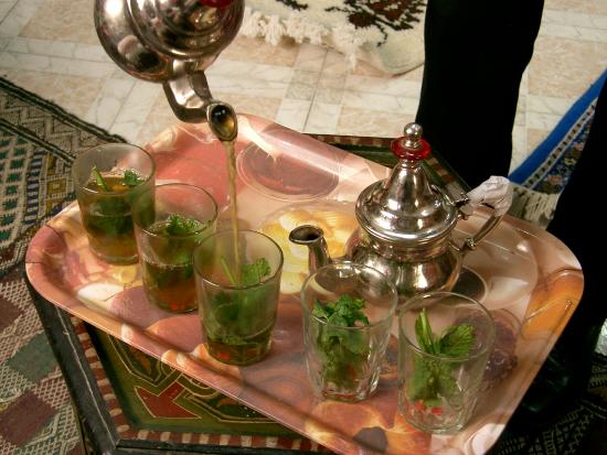 إبريق شاي أخضر مع عدد من الكؤوس وفيها نعنع