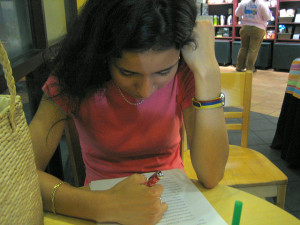 Woman reviewing an essay with a pen in her hand at a coffee shop table